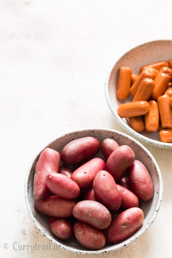 red potatoes and sausages in two white bowls