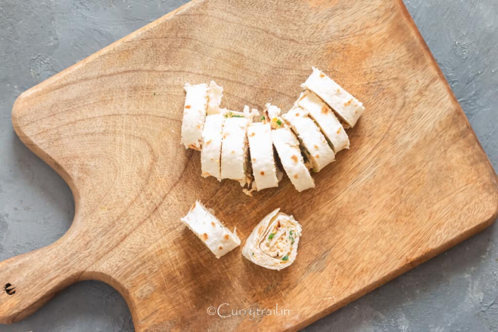 sliced pinwheels with creamy chicken filling inside on wooden board.