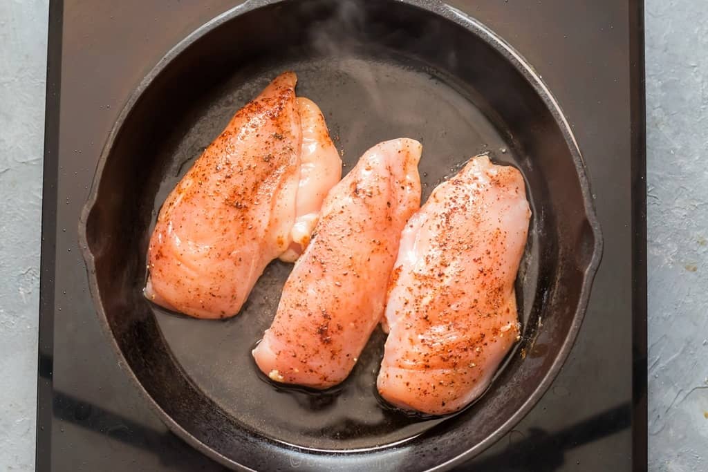 searing seasoned chicken breasts in cast iron pan.
