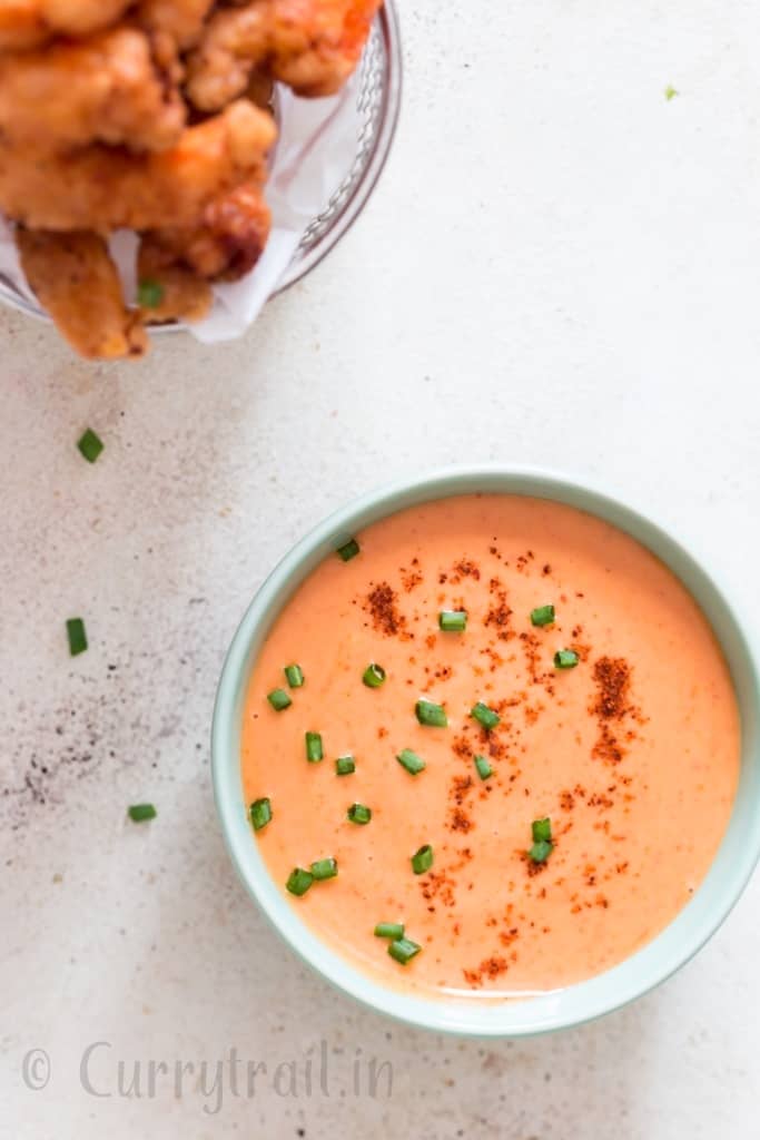 bang bang shrimp sauce in bowl with fried shrimps on side