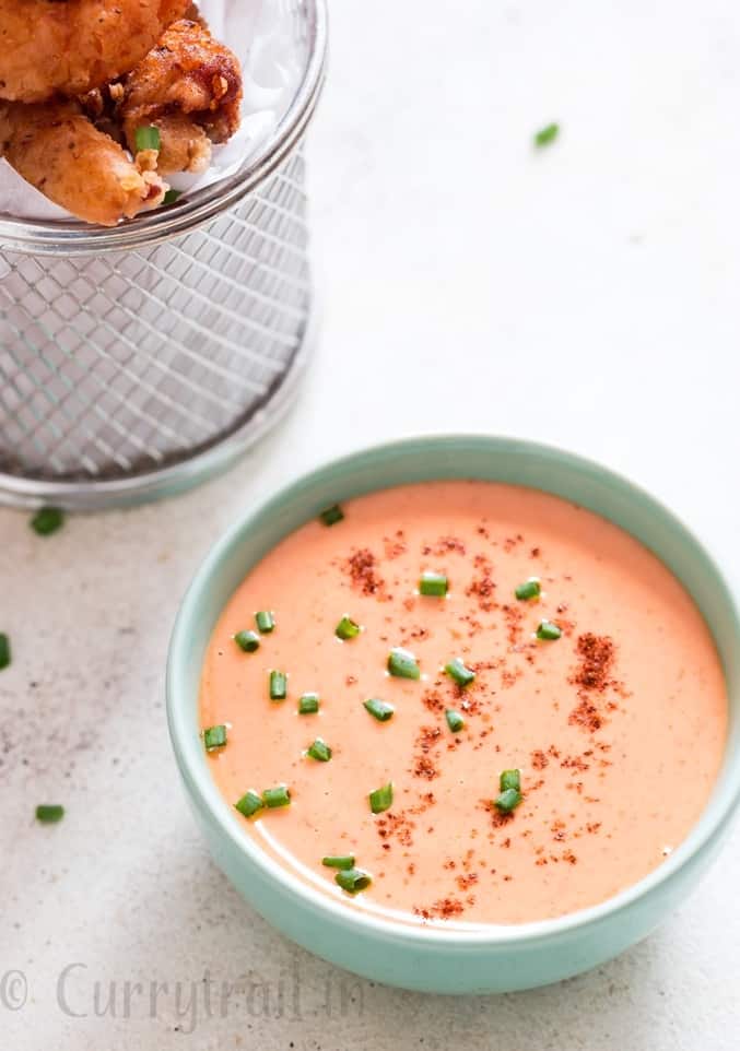 bang bang shrimp sauce in bowl with fried shrimps on side