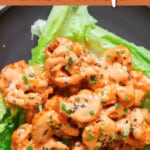 close up view of crispy fried shrimp with sweet spicy sauce drizzled over served on iceberg lettuce leaf.