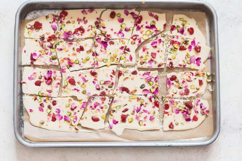 white chocolate bark with dried rose petals, pistachios and dried strawberries on parchment paper