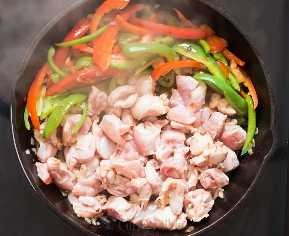 boneless chicken and vegetables cooked for Thai curry in a cast iron pan.