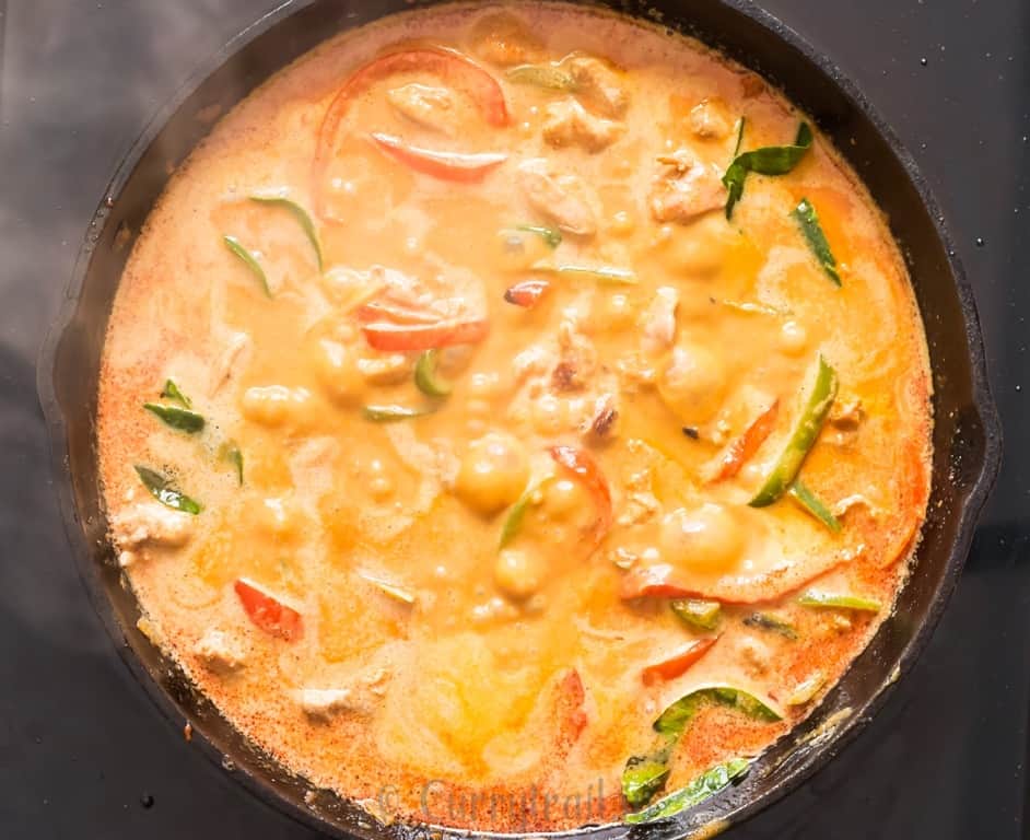 Thai chicken curry with coconut milk simmer in a skillet.