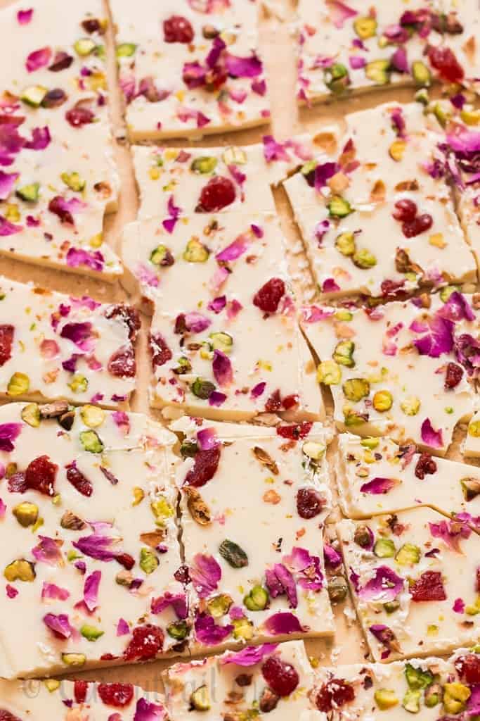 white chocolate bark with dried rose petals, pistachios and dried strawberries on parchment paper