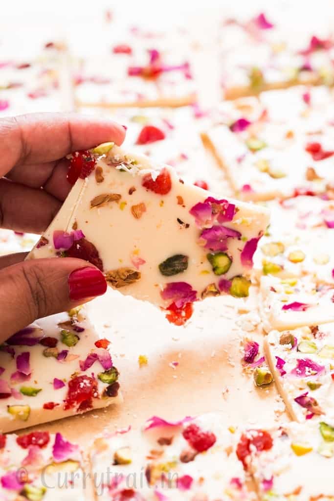 white chocolate bark with dried rose petals, pistachios and dried strawberries on parchment paper