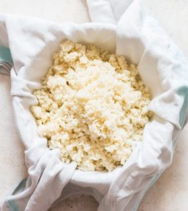 riced cauliflower in kitchen towel to make cauliflower breadsticks