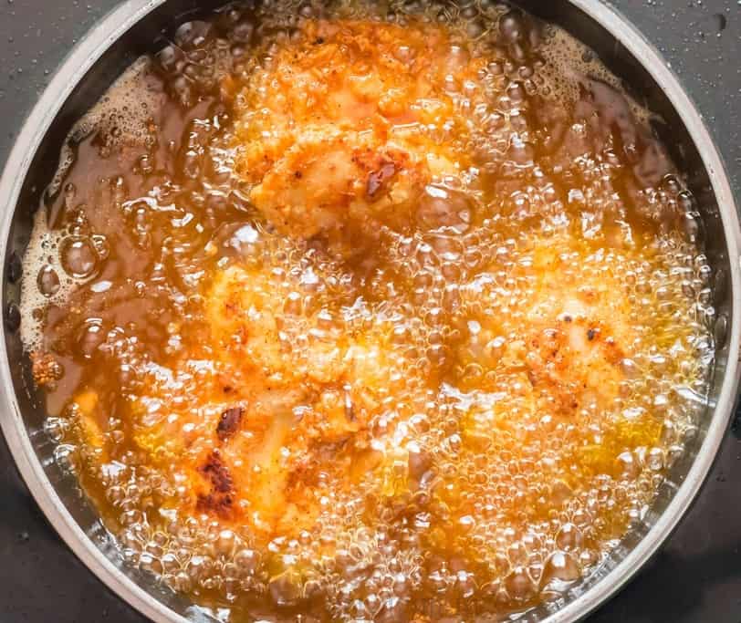 Deep frying chicken in a shallow pan.