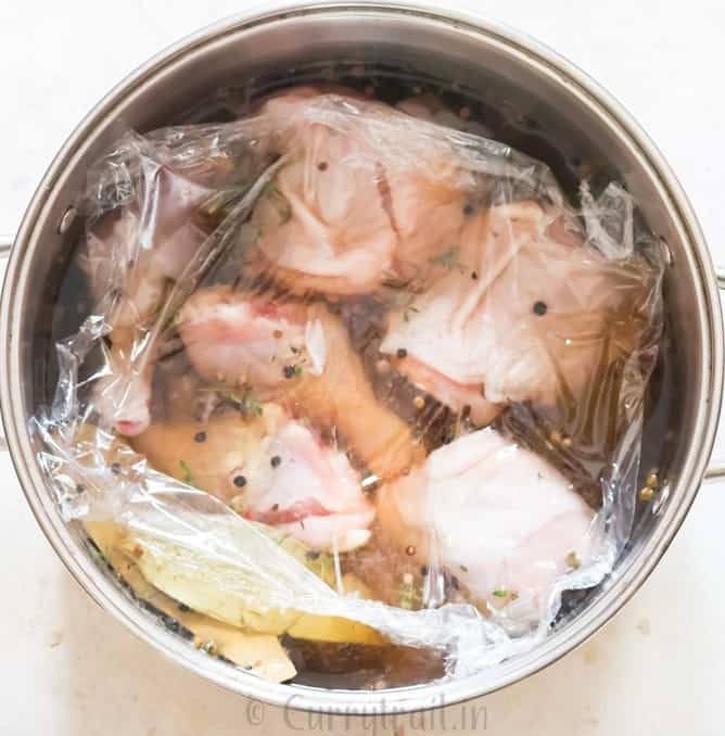 chicken pieces soaked in brine and covered with cling film.