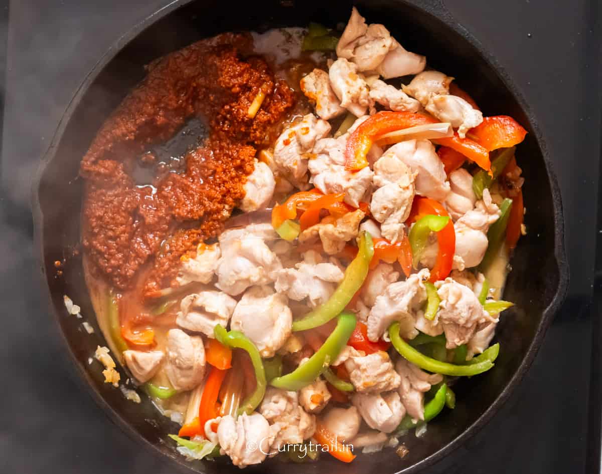 red Thai curry paste cooked with vegetables in a cast iron skillet.