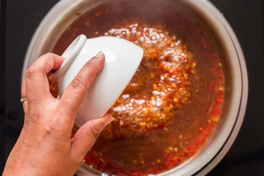 cooking homemade spicy sweet chili sauce in a pan.