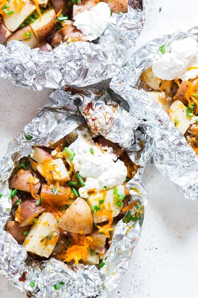 cheesy campfire grilled potatoes in foil packets with sour cream and scallions