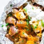 potatoes packed in aluminum foil with cheese and seasoning for grilling.