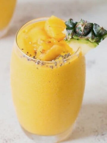 close up view of pineapple smoothie with pineapple wedge.