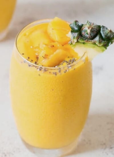 close up view of pineapple smoothie with pineapple wedge.