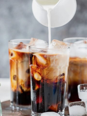 pouring cream into a glass for iced coffee.