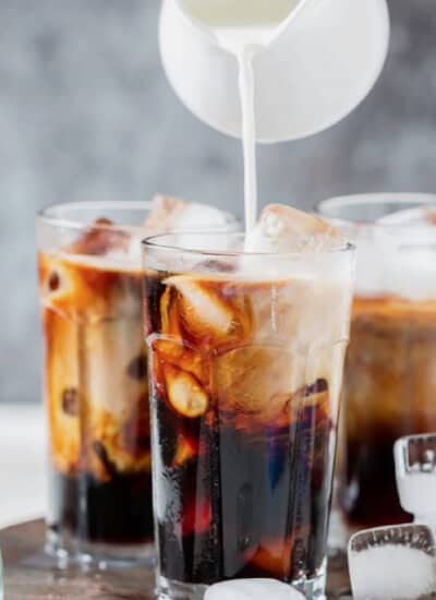 pouring cream into a glass for iced coffee.