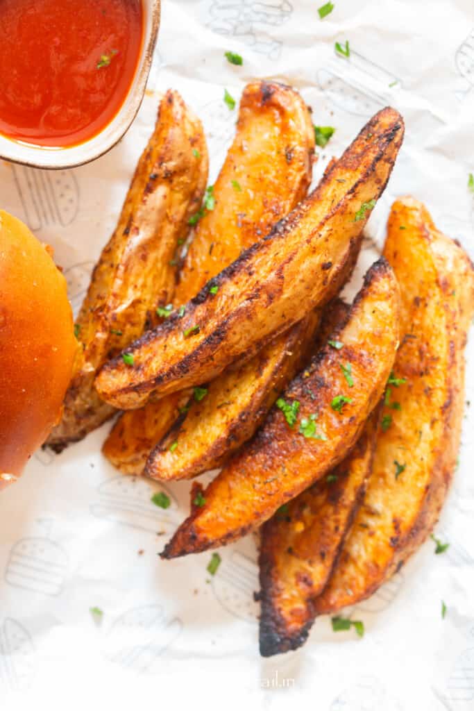 potato wedges served with burger and ketchup on the side.