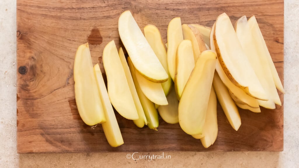 cutting potatoes into wedges on a wooden board.