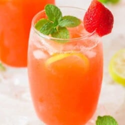 two glasses of strawberry lemonade garnished with fresh strawberry and mint leaves