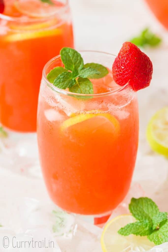 two glasses of strawberry lemonade garnished with fresh strawberry and mint leaves