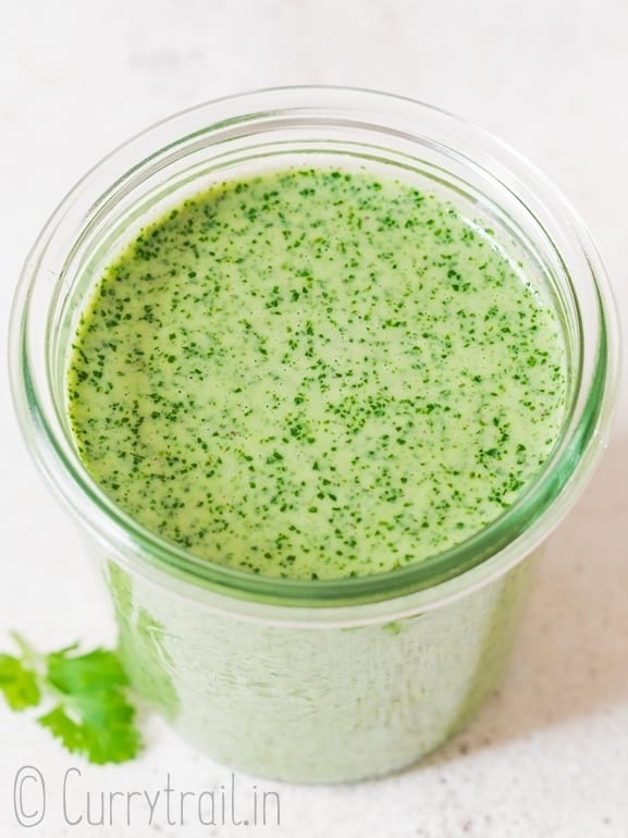 fresh cilantro lime sauce in air tight glass jar with fresh cilantro leaves placed on the surface