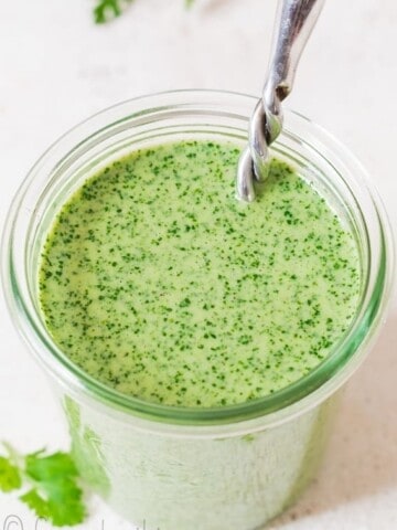 creamy cilantro sauce in glass jar with fancy spoon