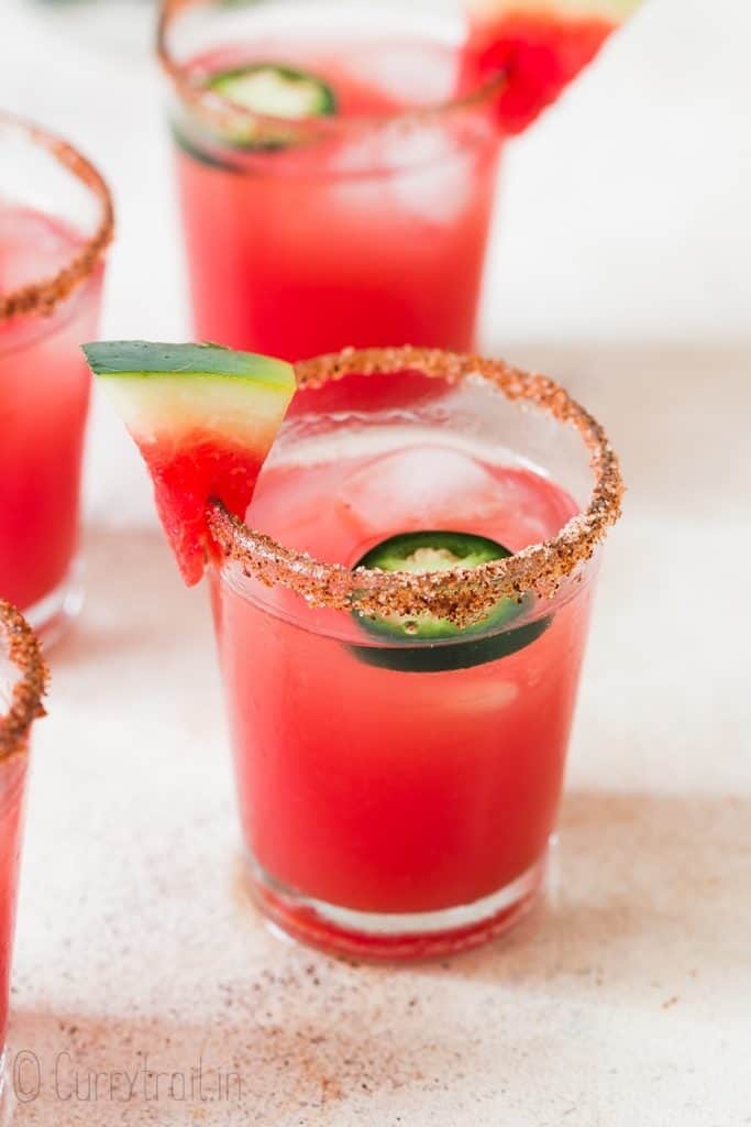 spicy watermelon margarita served in small glass with paprika salt rim