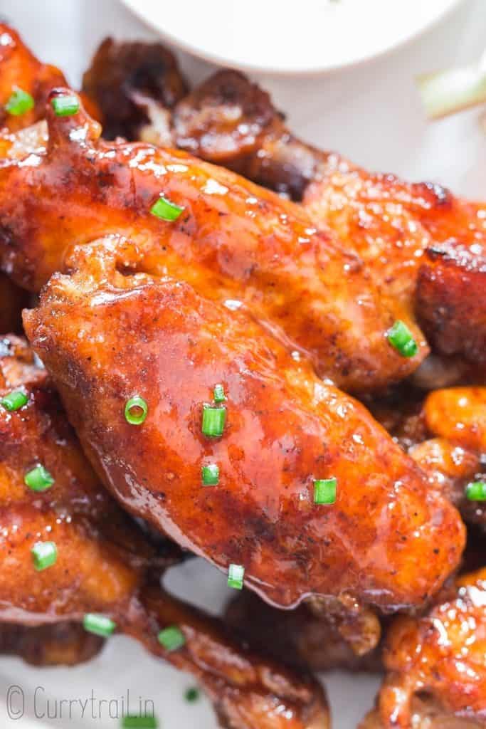 moist juicy sticky instant pot chicken wings on white plate with dipping sauce on side