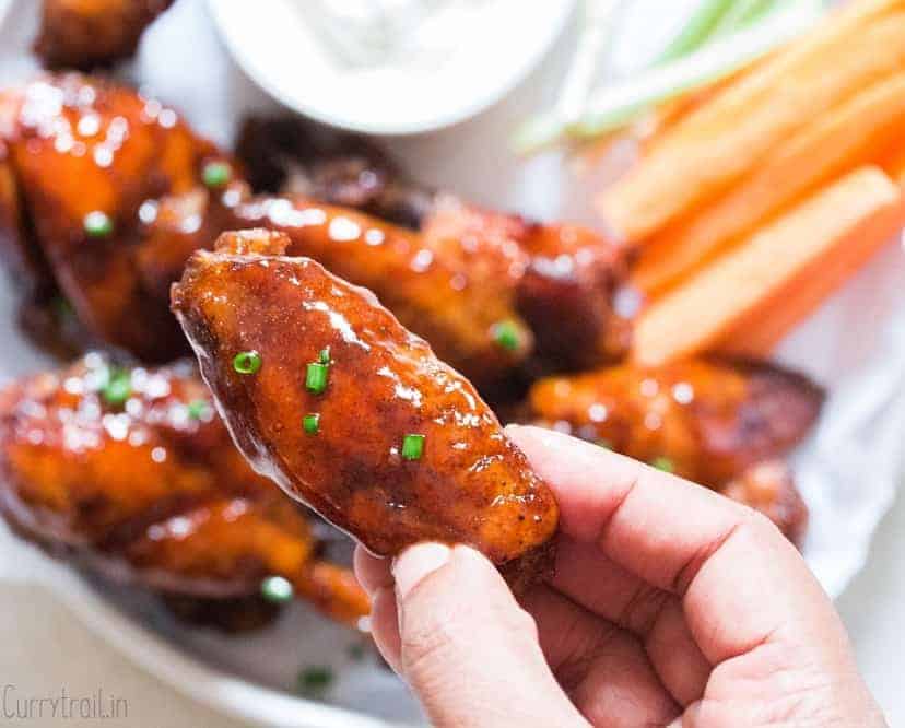 juicy instant pot chicken wings on white plate with a piece held in hand