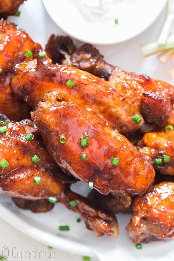 a white plate with instant pot chicken wings and a dipping sauce on the side