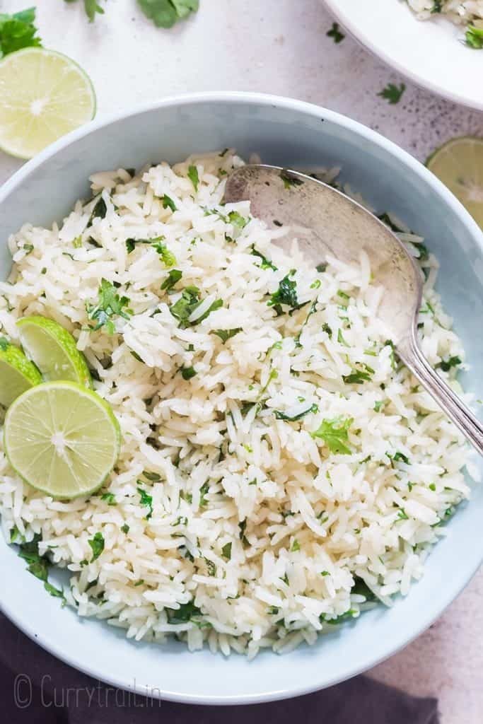 white bowl with cilantro and lime rice with lime slices on top with spoon
