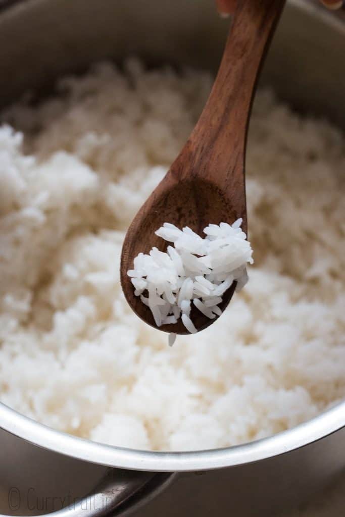 fluffy steamed rice in wooden spoon