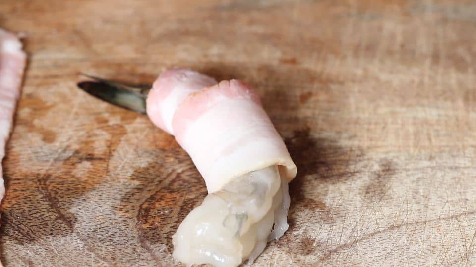 wrapping bacon strip over a shrimp.