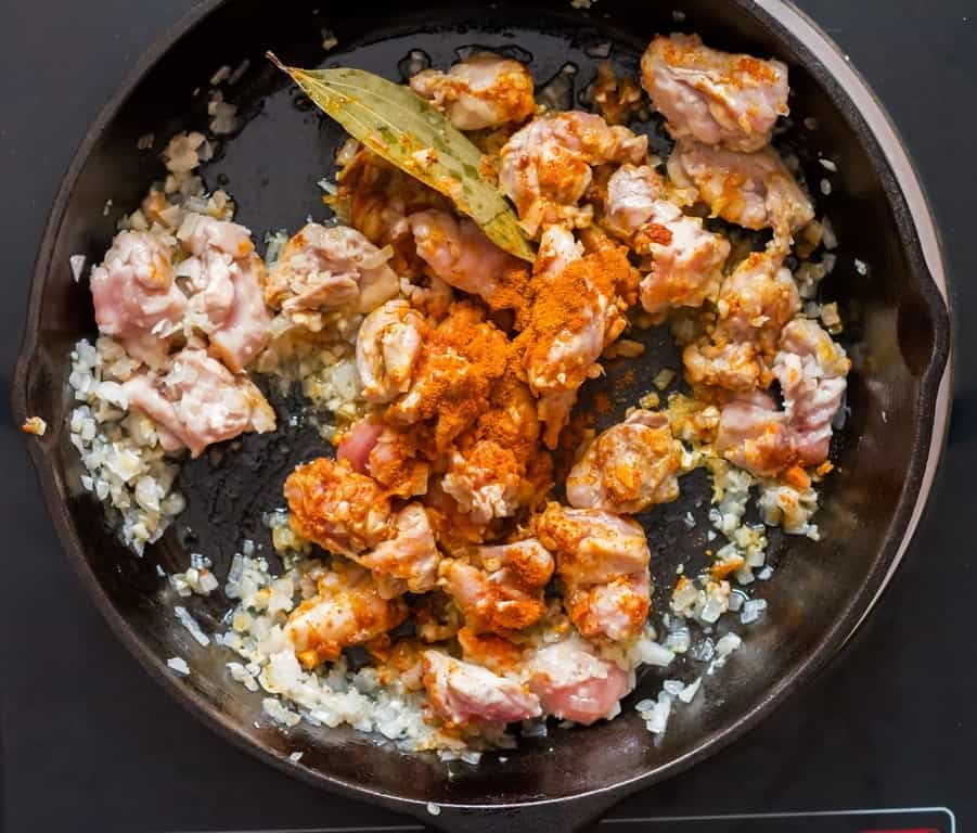 cooking chicken curry in cast iron pan with curry powder