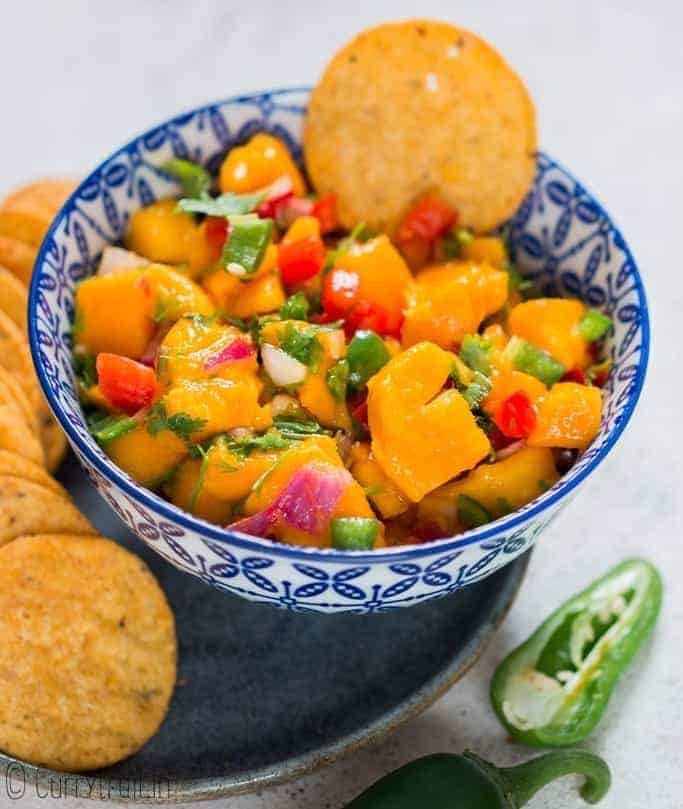 fresh summer salsa using mangoes with nachos in blue ceramic bowl