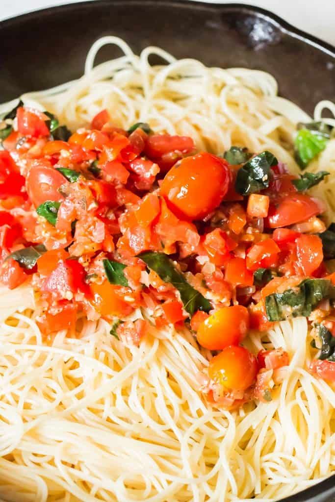 adding tomato bruschetta sauce to cooked pasta
