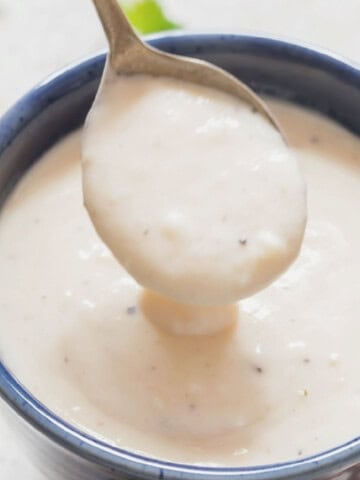 spoonful of rich, thick roasted garlic parmesan sauce in a bowl.
