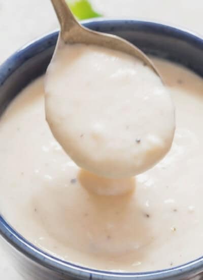 spoonful of rich, thick roasted garlic parmesan sauce in a bowl.
