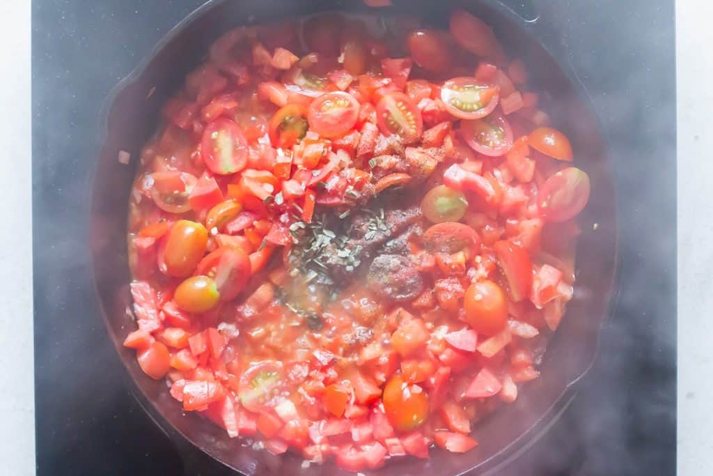 adding salt pepper dried herbs to ripe tomatoes