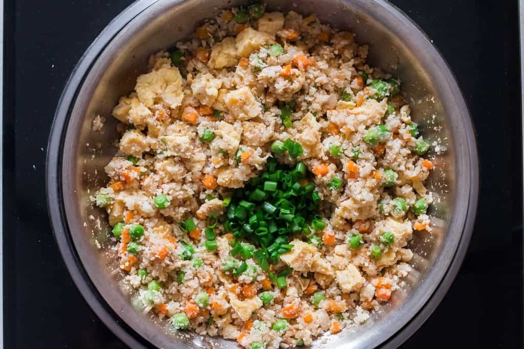 scallions added to cauliflower fried rice in skillet