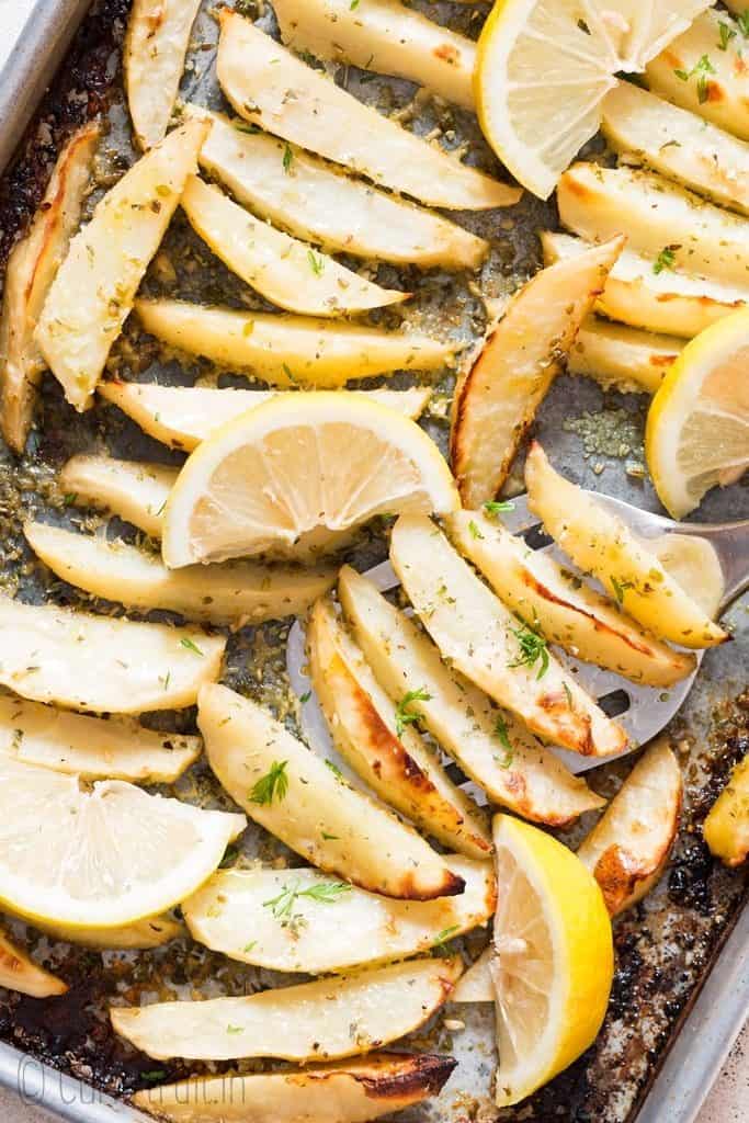 Greek lemon potatoes roasted in baking tray garnished with lemon slices