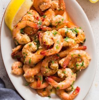 a white oval plate of lemon garlic shrimp.