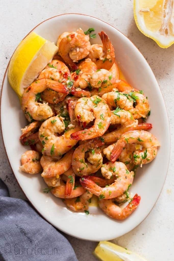 a white oval plate of lemon garlic shrimp