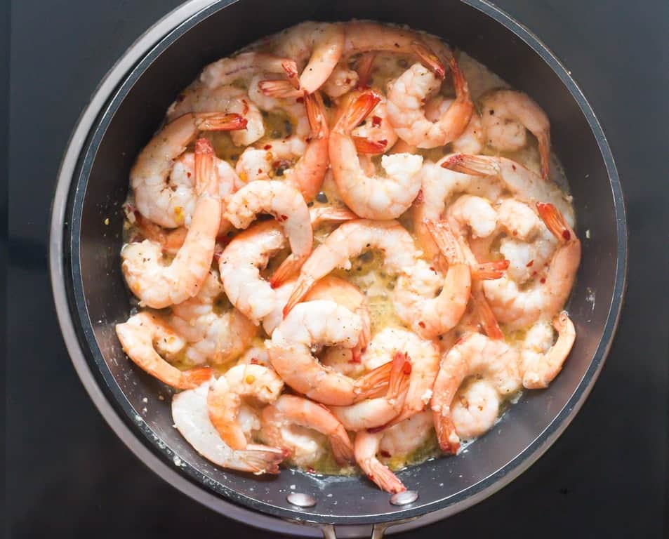 cooking lemon garlic shrimp in a skillet.