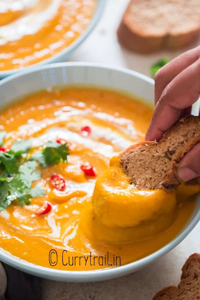 crusty bread dunked in pumpkin soup