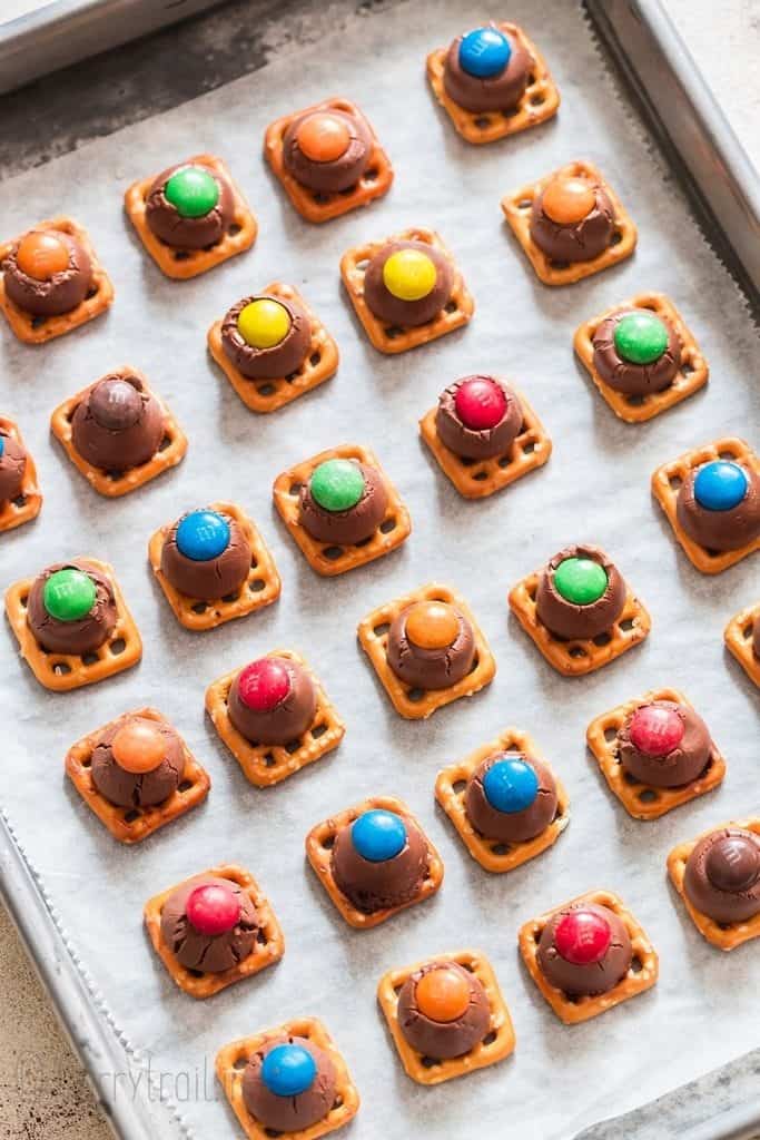 m&m pressed into hershey kisses over pretzel squares