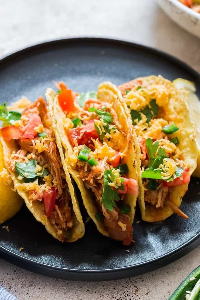 instant pot shredded chicken stuffed in tacos on ceramic plate