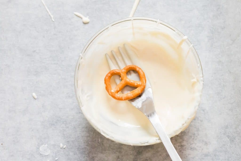 mojar pretzels en chocolate blanco derretido